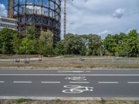 there is an empty street in front of a huge building under construction with trees around