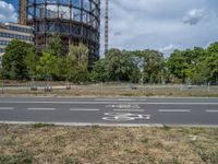 there is an empty street in front of a huge building under construction with trees around