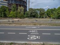 there is an empty street in front of a huge building under construction with trees around