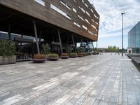 the view of a modern looking city sidewalk and outside seating area with flowers in the center