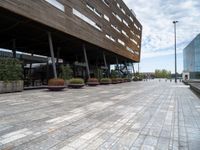 the view of a modern looking city sidewalk and outside seating area with flowers in the center