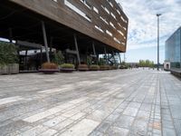 the view of a modern looking city sidewalk and outside seating area with flowers in the center