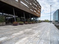 the view of a modern looking city sidewalk and outside seating area with flowers in the center