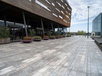 the view of a modern looking city sidewalk and outside seating area with flowers in the center