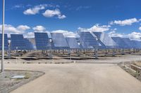 rows of solar panels against a blue sky with clouds in the background on a sunny day