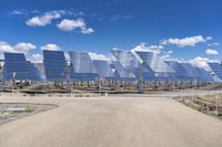 rows of solar panels against a blue sky with clouds in the background on a sunny day