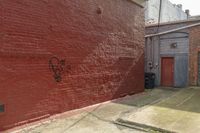 a red brick wall with graffiti on it and a fire hydrant on the curb next to an alley