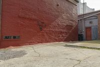 a red brick wall with graffiti on it and a fire hydrant on the curb next to an alley