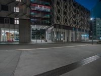 the night sky is darkened and the buildings lit up by brightly colored lights on the sidewalk