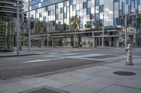 a city street with buildings and a street light and an empty sidewalk, in front of a large glass building