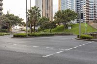 an empty street is surrounded by tall buildings and palm trees near the water entrance of an intersection