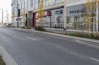 an empty street in a modern city with shops and trees on either side of it