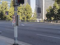 a metal fence next to a street with tall buildings in the background and no stopping sign on the sidewalk