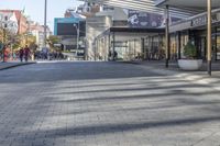 a view of a brick walkway from the street corner of a modern building area, along a sidewalk