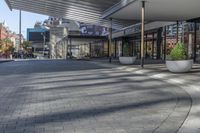 a view of a brick walkway from the street corner of a modern building area, along a sidewalk