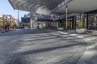 a view of a brick walkway from the street corner of a modern building area, along a sidewalk