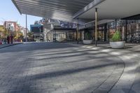 a view of a brick walkway from the street corner of a modern building area, along a sidewalk