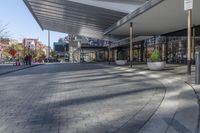 a view of a brick walkway from the street corner of a modern building area, along a sidewalk