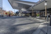 a view of a brick walkway from the street corner of a modern building area, along a sidewalk