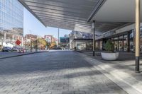 a view of a brick walkway from the street corner of a modern building area, along a sidewalk