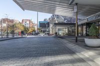 a view of a brick walkway from the street corner of a modern building area, along a sidewalk