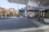 a view of a brick walkway from the street corner of a modern building area, along a sidewalk