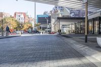 a view of a brick walkway from the street corner of a modern building area, along a sidewalk