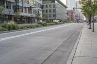 the empty city street is shown with a bus coming down it's road and several tall buildings