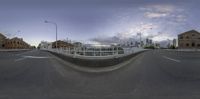 a 360 - pane view of a bridge across the street at dusk, with a traffic light