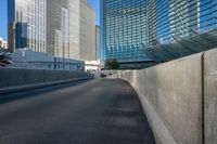 a highway leading to a tall glass structure and buildings in the distance, with one road empty except for vehicles