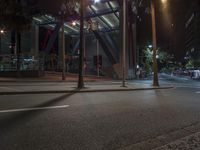 a street light and pole lights are on at night near a street that has buildings in the background