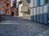 cobblestone driveway surrounded by modern buildings on sunny day with sun reflecting onto the windows