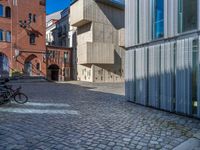 cobblestone driveway surrounded by modern buildings on sunny day with sun reflecting onto the windows