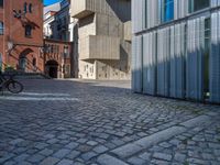 cobblestone driveway surrounded by modern buildings on sunny day with sun reflecting onto the windows