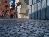 cobblestone driveway surrounded by modern buildings on sunny day with sun reflecting onto the windows