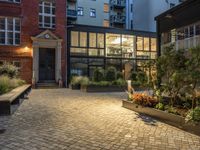 an exterior shot of two buildings at night, with lots of plants in the courtyard