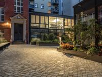 an exterior shot of two buildings at night, with lots of plants in the courtyard