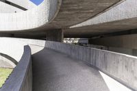 a modern concrete walkway that is winding through the park area of a public plaza,