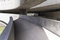 a modern concrete walkway that is winding through the park area of a public plaza,