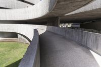 a modern concrete walkway that is winding through the park area of a public plaza,