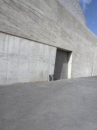 the parking garage door on this concrete building is open to let in some light in