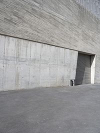 the parking garage door on this concrete building is open to let in some light in