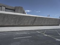 an empty city sidewalk next to a cement building with a sloped roof and curve - like edge