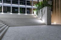 a set of concrete stairs in an outdoor area, which is lit up by multiple windows