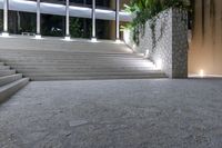 a set of concrete stairs in an outdoor area, which is lit up by multiple windows