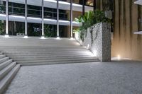 a set of concrete stairs in an outdoor area, which is lit up by multiple windows