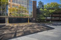 the sun shines on a parking garage with trees surrounding it, which reflect in the windows