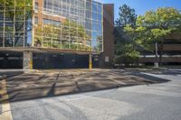 the sun shines on a parking garage with trees surrounding it, which reflect in the windows