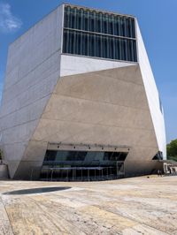 a tall gray building with glass and cement on the outside of it's sides
