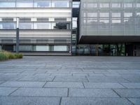 a person rides their skate board in a courtyard area with grey stone floors and many windows